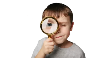 Image of a boy holding a magnifying glass looking directly into the camera to represent the importance of spotting billing errors in medical bills.